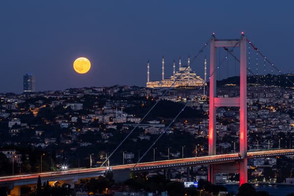 Une super lune bleue se lève derrière le pont des martyrs du 15 juillet et la mosquée Camlıca à Istanbul, le 19 août 2024.